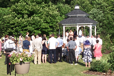 Photo of a crowd gathering for a wedding ceremony at the gazebo on the White Garden Inn property